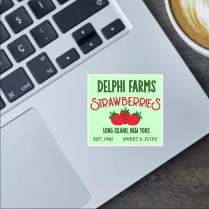 May include: A green and white sticker with the text "DELPHI FARMS STRAWBERRIES" in red and green lettering. The sticker also includes the text "LONG ISLAND, NEW YORK" and "EST 1982 SWEET & JUICY". Three red strawberries are pictured on the sticker.