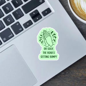 May include: A green sticker with a praying hands design and the text "Oh Golly, The Road's Getting Bumpy".