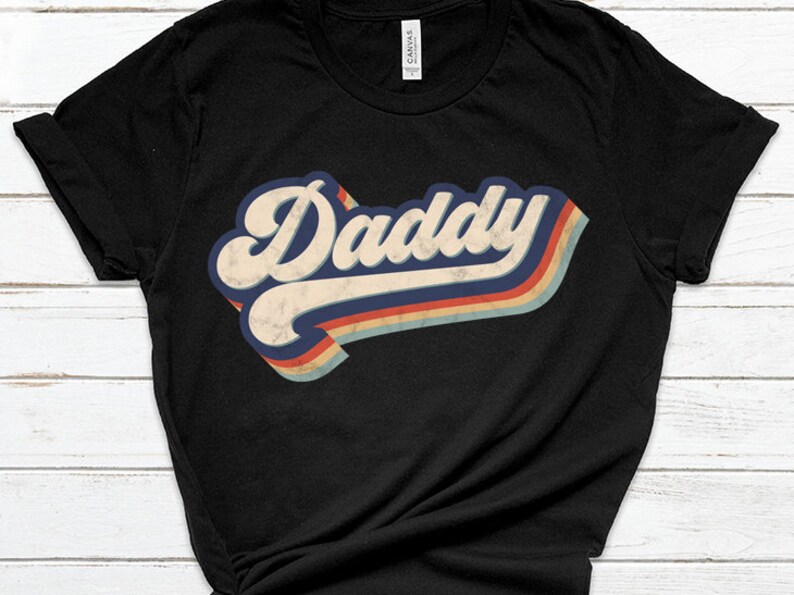 May include: Black t-shirt with a retro-style graphic that says "Daddy" in a colorful, faded rainbow design.