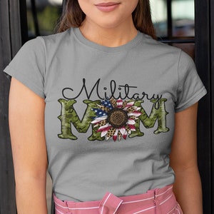 Może przedstawiać: Szary T-shirt z zielonym nadrukiem kamuflażu i słonecznikiem z wzorem amerykańskiej flagi. Na koszulce nadrukowany jest tekst "Military Mom".