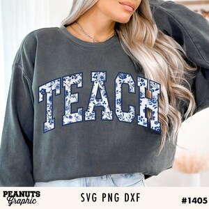May include: A dark gray sweatshirt with the word "TEACH" printed in white letters with a blue floral pattern.