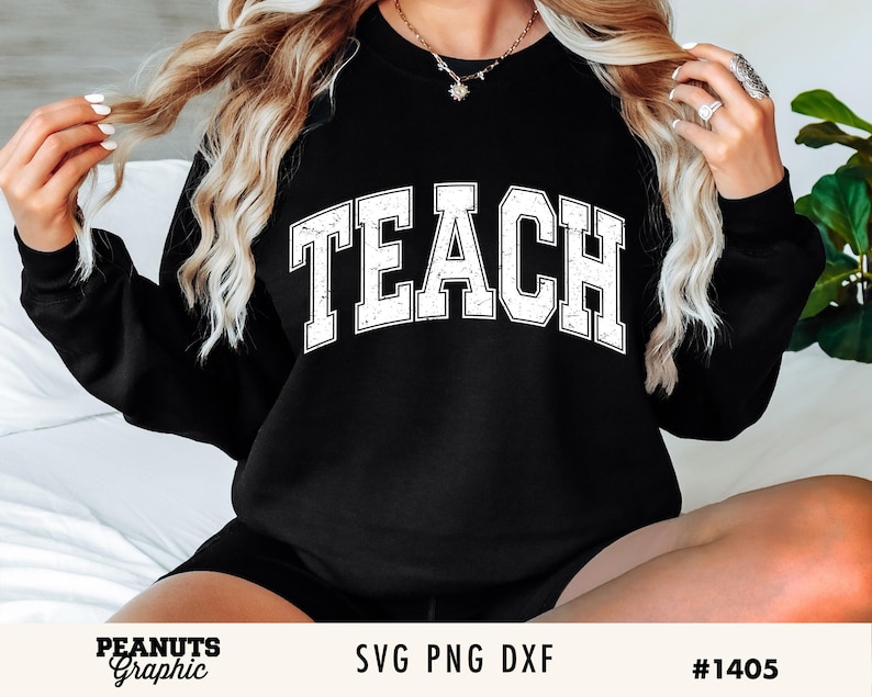 May include: A black sweatshirt with the word "TEACH" in white distressed lettering. The sweatshirt is worn by a person with long blonde hair.