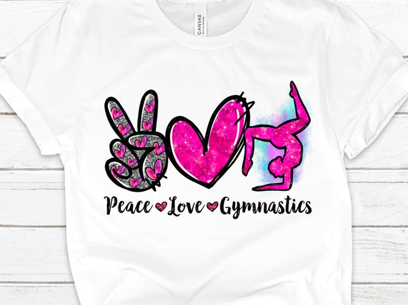 May include: White t-shirt with a pink peace sign, heart, and a gymnast in a backbend pose. The text "Peace Love Gymnastics" is printed below the images.