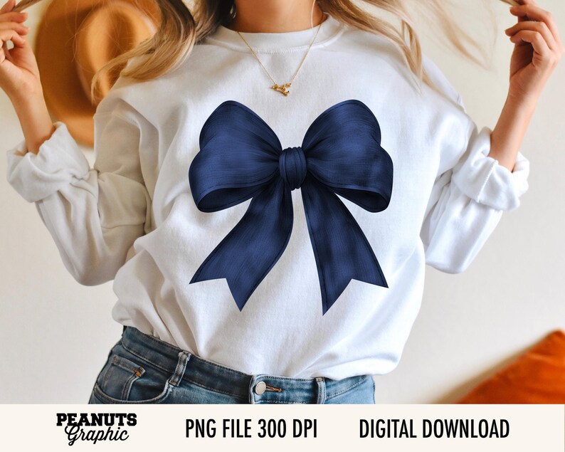 Op de afbeelding: Witte sweatshirt met een grote, marineblauwe strik. De strik staat centraal op de voorkant van de trui. De tekst "PEANUTS Graphic" staat linksonder, met "PNG FILE 300 DPI" en "DIGITAL DOWNLOAD" rechts.