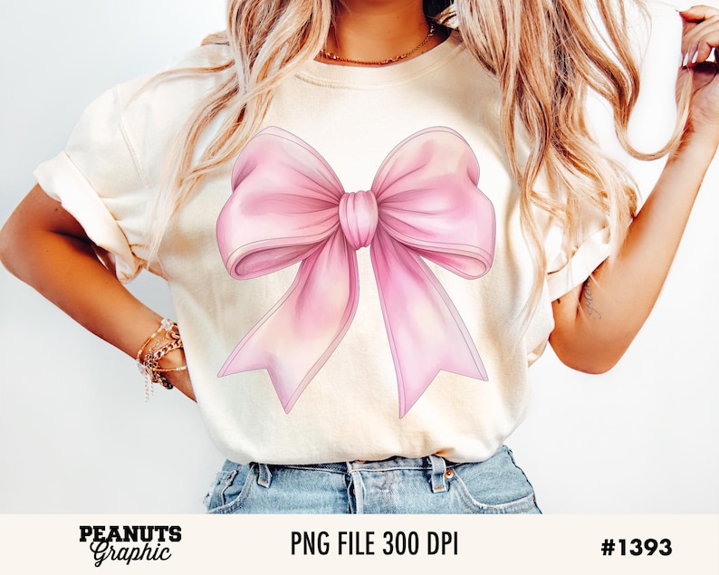 May include: A white t-shirt with a large pink bow graphic. The bow is drawn in a watercolor style with soft edges.