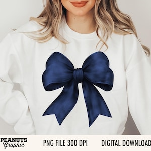 Op de afbeelding: Witte sweatshirt met een grote, marineblauwe strik. De strik heeft een gedetailleerd, getextureerd uiterlijk. De tekst "PNG FILE 300 DPI" en "DIGITAL DOWNLOAD" staan onderaan. Het merk "Peanuts Graphic" is ook zichtbaar.