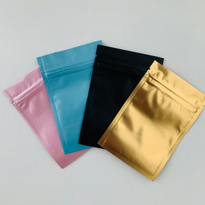 May include: Four resealable plastic bags in different colors: pink, light blue, black, and gold.