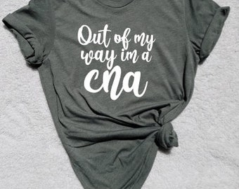 May include: A dark green t-shirt with the text "Out of my way I'm a CNA" in white lettering.