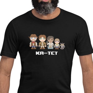 Könnte beinhalten: Schwarzes T-Shirt mit einem Aufdruck von fünf Comicfiguren und dem Text "KA-TET" auf der Vorderseite.