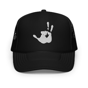 May include: Black trucker hat with a white embroidered handprint design. The hat has a mesh back and a curved peak. The handprint is centered on the front panel.