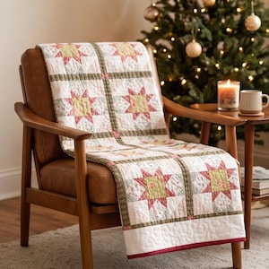 May include: A quilted throw blanket featuring a repeating star pattern in shades of muted red, pale green, and cream. The quilt is constructed with square blocks separated by thin olive green sashing and finished with a solid dark red border.