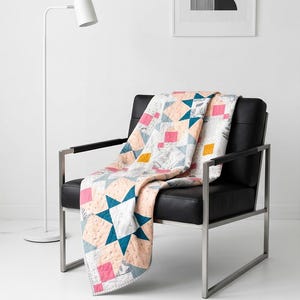 May include: A patchwork quilt featuring a geometric star pattern in shades of peach, teal, white, pink, and mustard yellow. The fabric displays a mix of solid colors and subtle botanical prints, with visible stitching throughout the quilted surface.