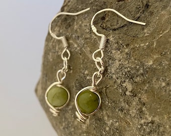 May include: A pair of silver earrings with green stone beads. The earrings are wire wrapped and have a simple design.