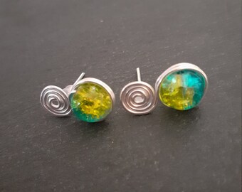 May include: A pair of earrings with a silver spiral design and a round green and yellow glass bead.