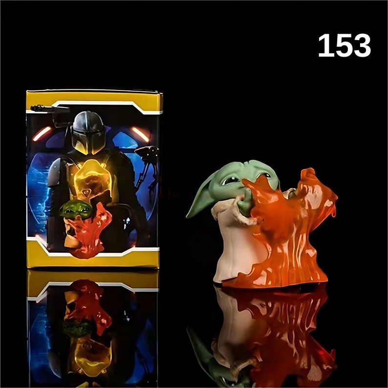 May include: A green and orange action figure of a character from the Star Wars franchise. The figure is holding a small orange object in its hands. The figure is standing on a black surface. The figure is part of a set of action figures. The set is packaged in a yellow box with a picture of a character from the Star Wars franchise on the front. The box is labeled with the number 153.
