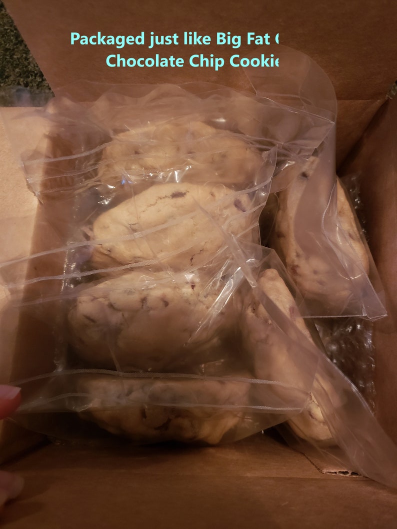 Puede incluir: Una caja de cart&oacute;n llena de varias galletas grandes con chispas de chocolate, envueltas individualmente en pl&aacute;stico transparente. Las galletas son de color marr&oacute;n claro con chispas de chocolate visibles. El texto en la caja dice: "Packaged just like Big Fat Chocolate Chip Cookie."