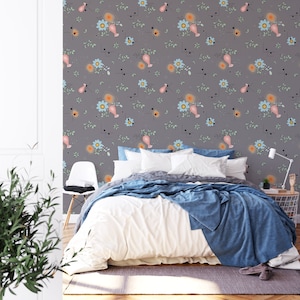 Peut inclure: Une chambre à coucher avec un mur gris orné d'un papier peint à motifs floraux. Le papier peint présente un motif répétitif de fleurs roses et bleues avec des feuilles vertes et des formes géométriques noires. Un lit blanc avec une couette blanche et une couverture bleue se trouve dans la pièce. Une chaise blanche se trouve dans le coin de la pièce.