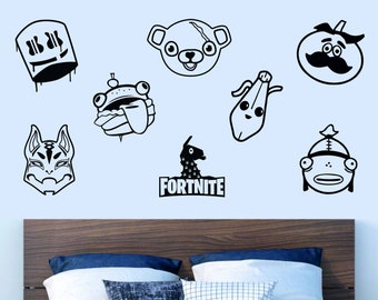 Könnte beinhalten: Ein Set aus schwarzen und weißen Fortnite-Charakter-Aufklebern, darunter ein Lama, ein Bär, ein Fisch, ein Kürbis, eine Banane und ein Schädel. Die Aufkleber befinden sich an einer hellblauen Wand über einem Holz-Kopfteil mit zwei Kissen.