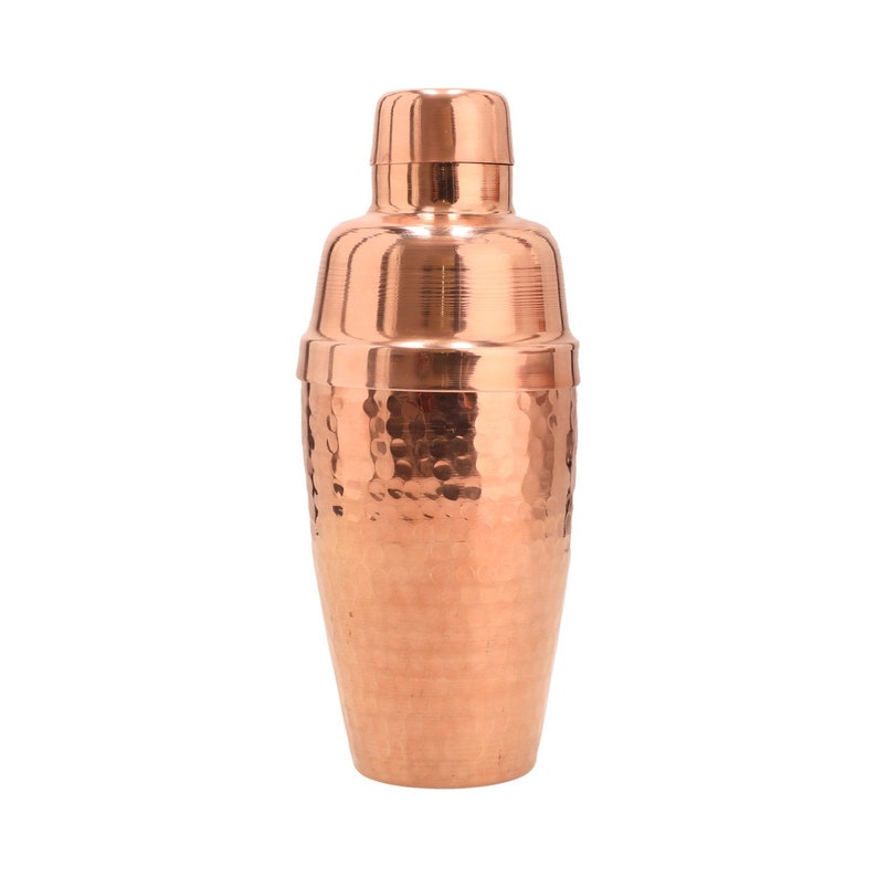 May include: A copper cocktail shaker with a hammered finish. The shaker has a classic design with a rounded body and a lid with a pour spout.