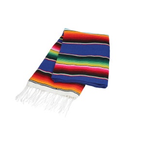 Könnte beinhalten: Eine bunte mexikanische Decke mit roten, gelben, grünen und blauen Streifen. Die Decke hat weiße Fransen an den Rändern und ist in der Mitte gefaltet.