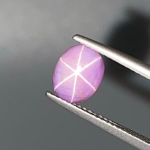 May include: A pink star sapphire gemstone with a six-pointed star in the center.