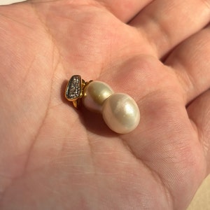 May include: A pair of white pearl earrings with a gold setting and a small diamond accent.