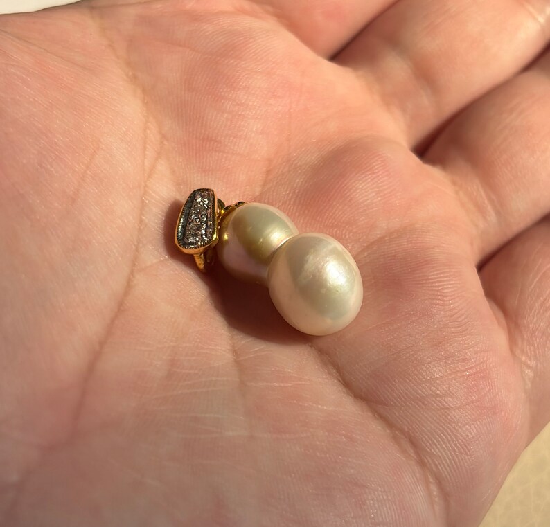 May include: A pair of white pearl earrings with a gold setting and a small diamond accent.