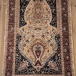 May include: A traditional Persian rug with a cream-colored center featuring intricate floral designs. The rug has a dark blue border with red and gold accents. The rug has a fringe on all sides.
