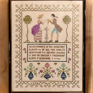 以下が含まれることがあります： 花柄のクロスステッチ刺繍が施された額縁。思い出についての言葉が書かれており、"Remembrance is the sweetest flower of all this world's perfuming memory guards it sun or shower friendship keeps it blooming"と書いてあります。刺繍は1936年製で、M.C.B.の署名があります。