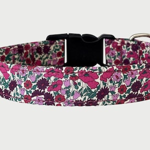 May include: A pet collar featuring a dense floral pattern in shades of magenta, deep purple, and dark green. The collar includes a black plastic side-release buckle and a silver-toned metal D-ring for attachment, secured with visible stitching.
