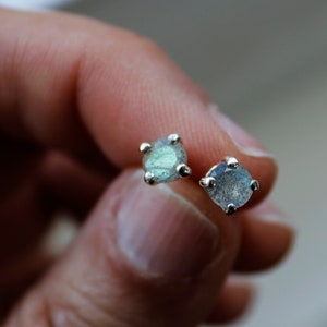 Op de afbeelding: Een paar zilveren oorbel studs met iriserende groene en blauwe labradorite edelstenen.