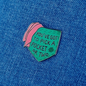 Può includere: Spilla in smalto verde con una tasca in tessuto rosa e il testo "You've got to pick a pocket or two".