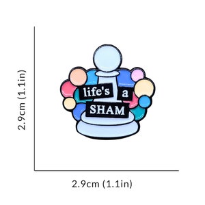 May include: A white chess pawn with a colorful circle design around it. The pawn has the words "life's a sham" written on it.