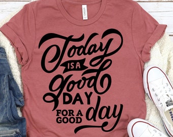 May include: A maroon t-shirt with the text "Today is a good day for a good day" in black lettering.