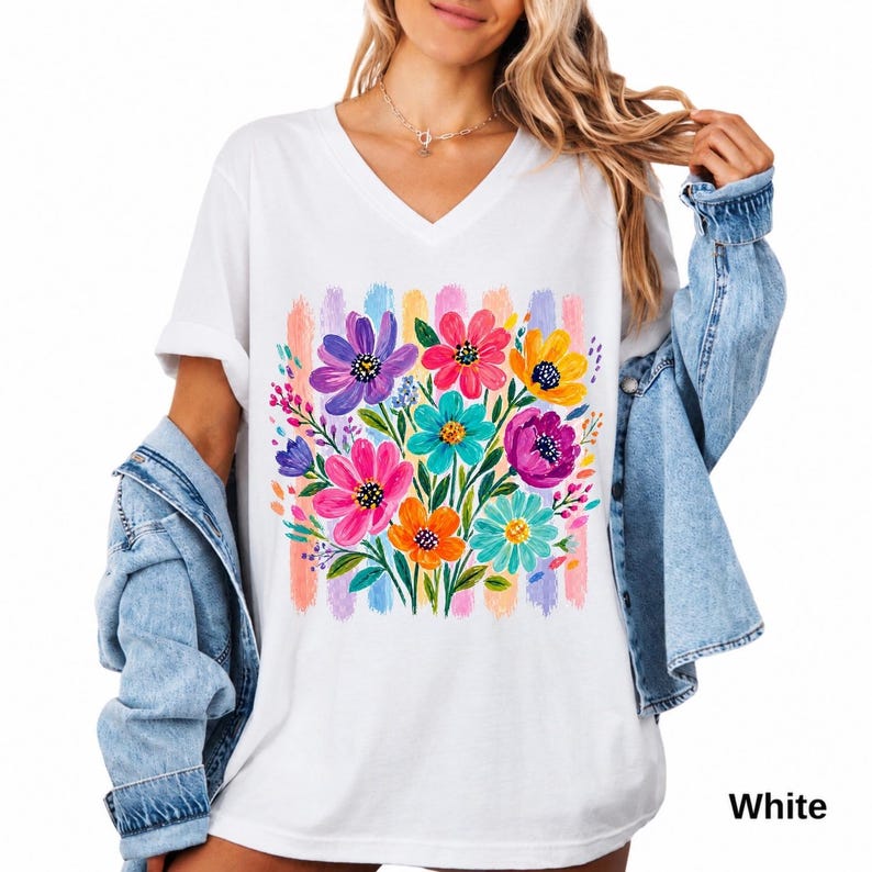 Op de afbeelding: Een wit T-shirt met V-hals voorzien van een kleurrijke afbeelding van een bloemenboeket met paarse, roze, gele en turquoise bloemen. Het ontwerp is geplaatst tegen een achtergrond van verticale pastelkleurige penseelstreken in roze, geel en blauw.