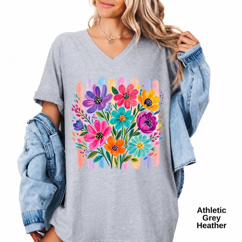Op de afbeelding: Een atletisch grijs gem&ecirc;leerd T-shirt met V-hals en een kleurrijke afbeelding van geschilderde bloemen in tinten paars, roze, geel en taling, tegen een achtergrond van verticale pastelkleurige penseelstreken. De tekst Athletic Grey Heather is zichtbaar.