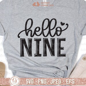 Puede incluir: Una camiseta gris con texto negro que dice "hello nine" con un peque&ntilde;o s&iacute;mbolo de coraz&oacute;n despu&eacute;s de la palabra "hello".