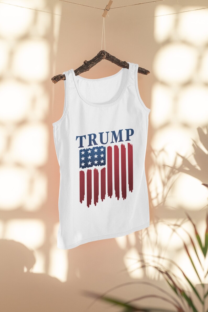 May include: White tank top with a blue and red American flag design and the word "TRUMP" printed in blue.
