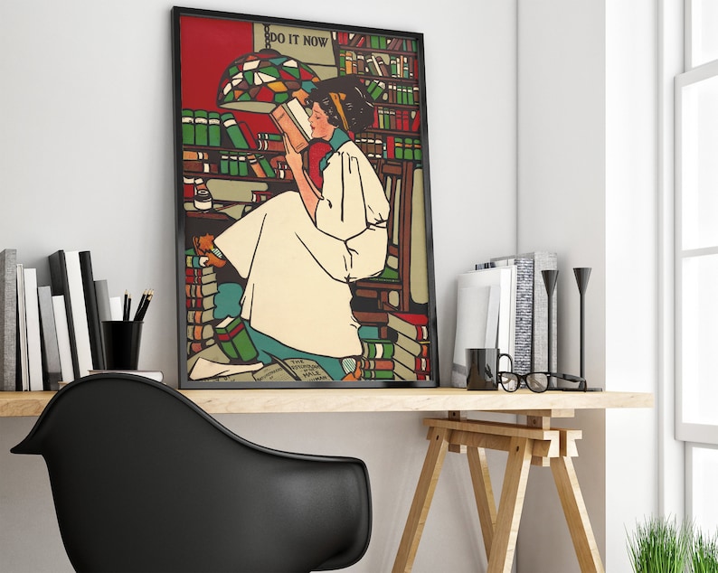 Puede incluir: Un p&oacute;ster vintage enmarcado con una mujer sentada sobre una pila de libros. El p&oacute;ster est&aacute; colocado contra una pared blanca y presenta el texto "Do It Now".