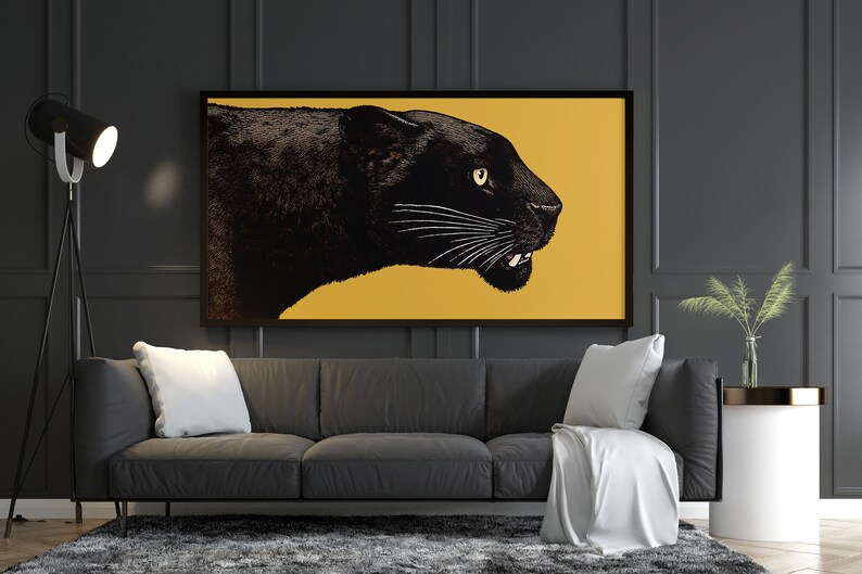 K&ouml;nnte beinhalten: Ein schwarzer Panther vor gelbem Hintergrund in einem gerahmten Druck, der &uuml;ber einem grauen Sofa mit wei&szlig;en Kissen h&auml;ngt.