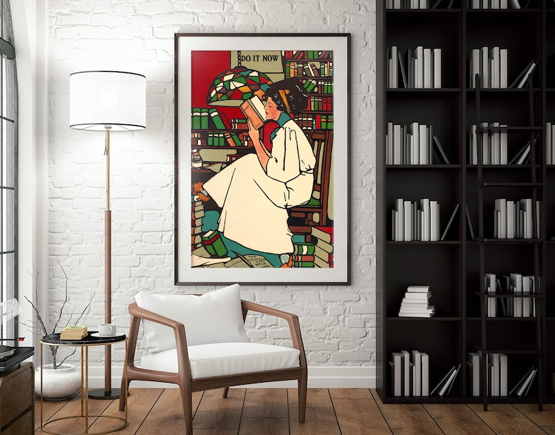 Puede incluir: Un p&oacute;ster vintage con una mujer leyendo un libro en una biblioteca. El p&oacute;ster est&aacute; enmarcado y tiene el texto "DO IT NOW" en la parte superior. La mujer lleva un vestido blanco y tiene el pelo oscuro. La biblioteca est&aacute; llena de estanter&iacute;as y una l&aacute;mpara de cristal de colores.