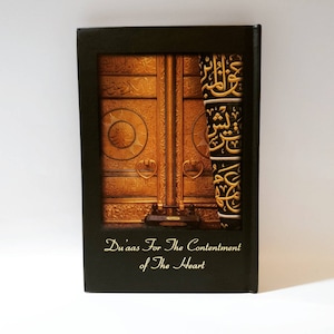 May include: A black journal featuring a gold image of the Kaaba, the holiest site in Islam. The journal is inscribed with the words "Du'aas For The Contentment of The Heart" on the front.