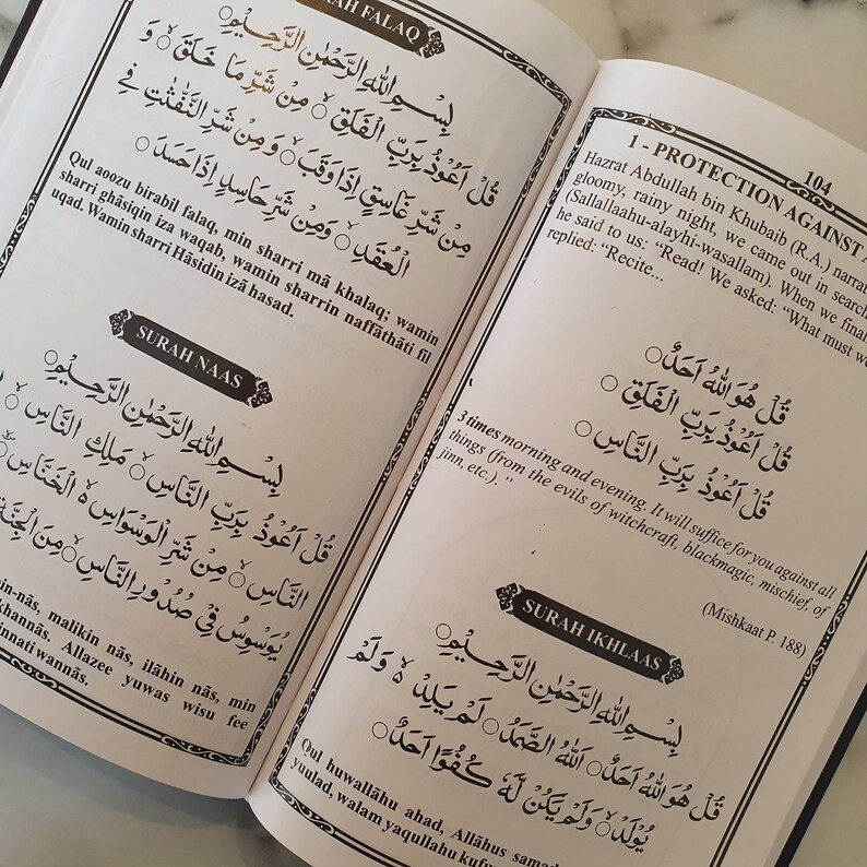 May include: A page from a book with Arabic text in black ink on a white background. The text is divided into two columns. The left column is titled "Surah Naas" and the right column is titled "Protection Against".