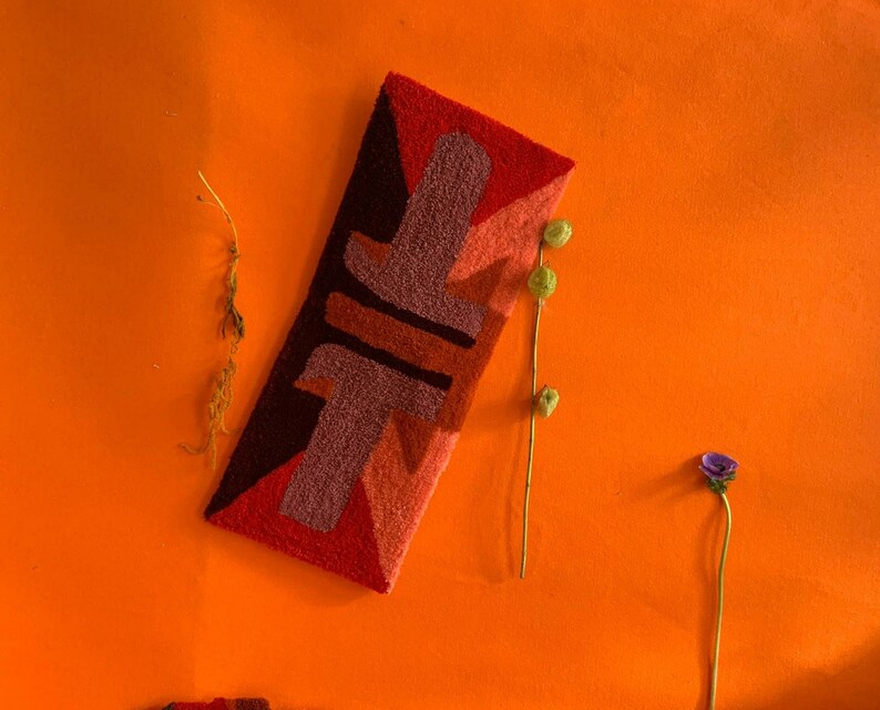 Pu&ograve; includere: Un tappeto astratto colorato con forme geometriche in tonalit&agrave; di rosso, arancione, marrone e rosa. Il tappeto &egrave; su uno sfondo arancione brillante.