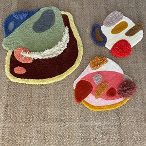 May include: Three colorful abstract rug shapes with a variety of textures and colors, including green, brown, yellow, red, pink, white, and blue.