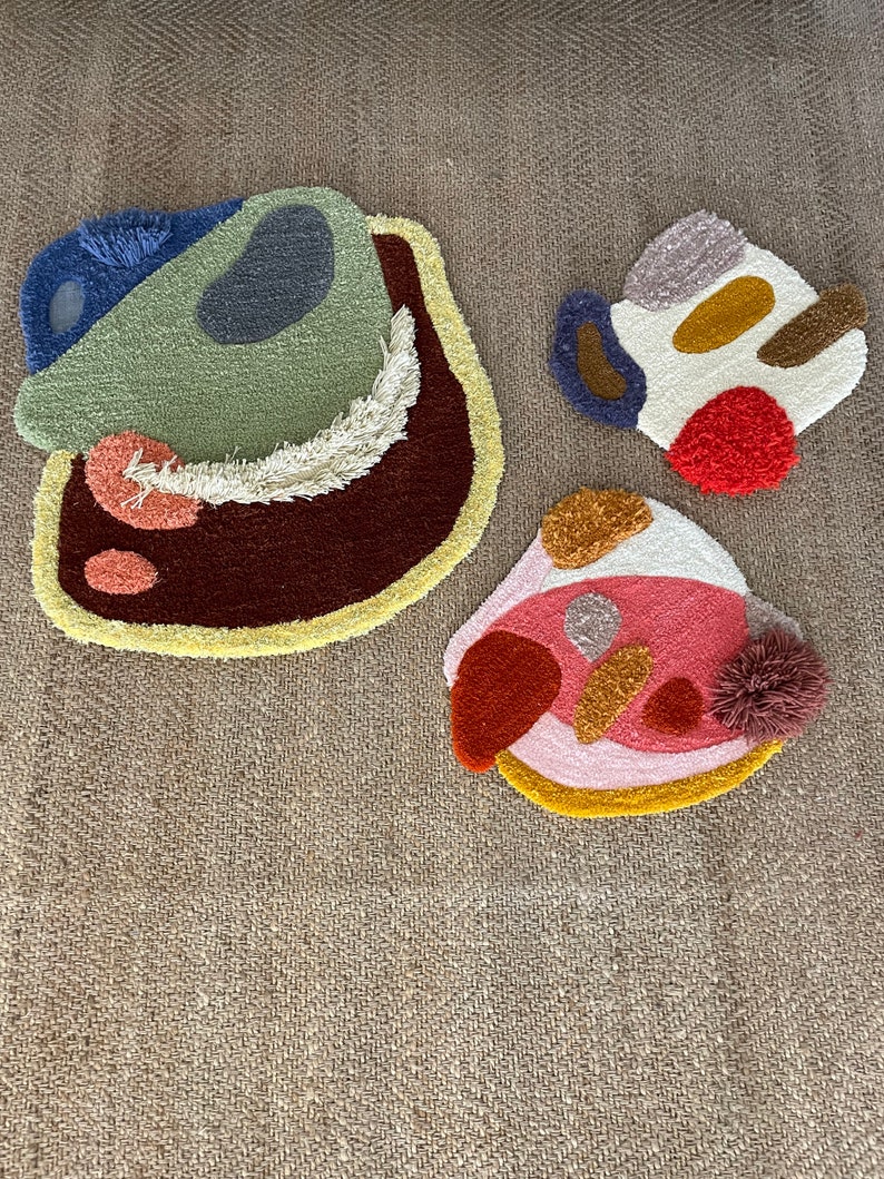 May include: Three colorful abstract rug shapes with a variety of textures and colors, including green, brown, yellow, red, pink, white, and blue.