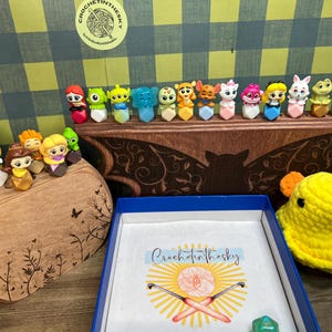 May include: A wooden shelf with a bat design holds a collection of small plastic figurines. The figurines are colorful and feature characters from popular movies and TV shows. The shelf is labeled "Crochet in the Sky".