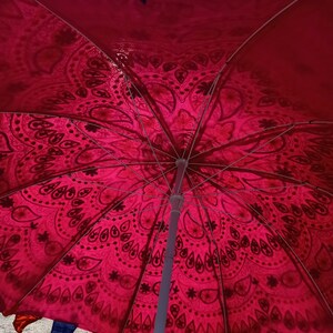Może przedstawiać: Czerwono-biały parasol z wzorem i białą metalową ramą. Parasol jest otwarty, a tkanina jest napięta.