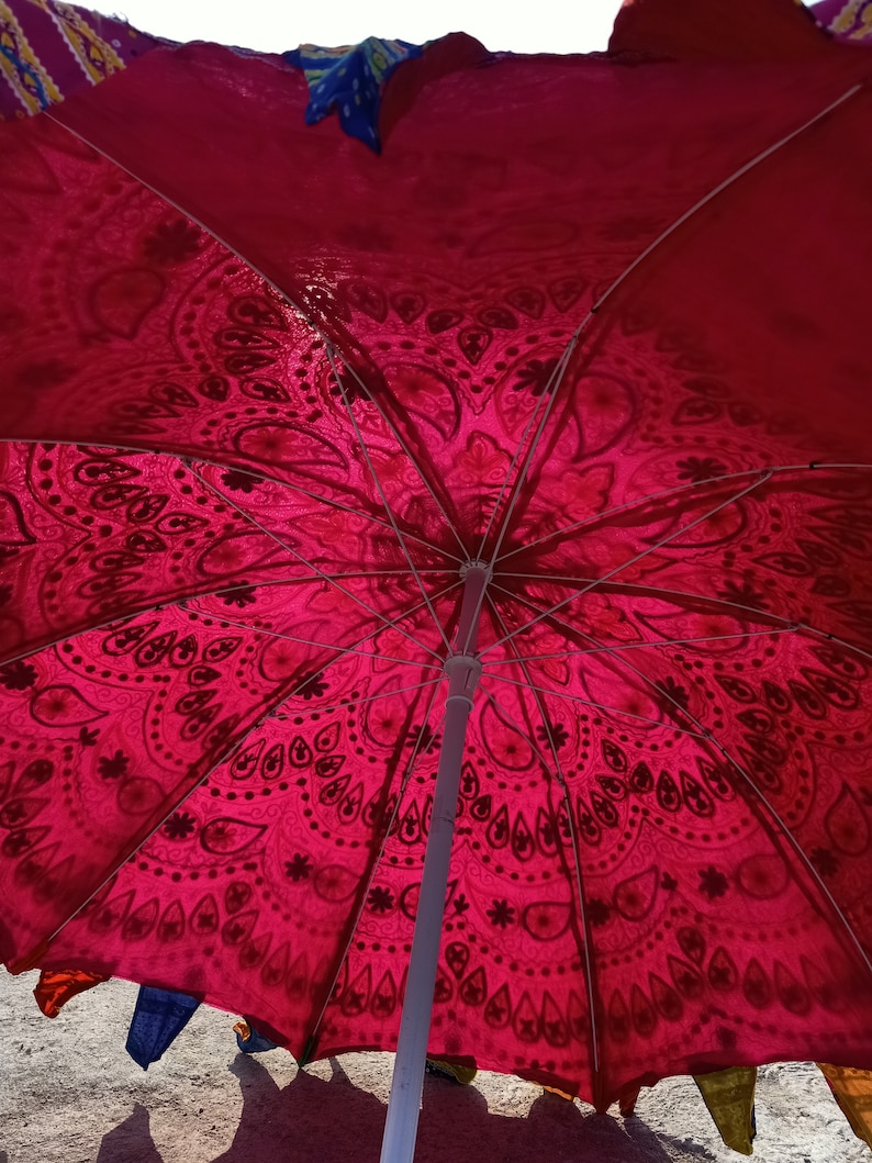 Może przedstawiać: Czerwono-biały parasol z wzorem i białą metalową ramą. Parasol jest otwarty, a tkanina jest napięta.