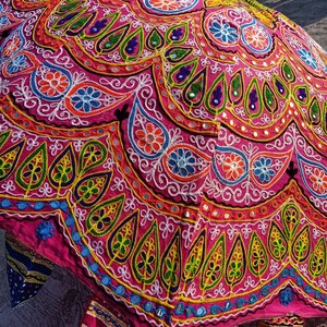 Może przedstawiać: R&oacute;żowy i wielokolorowy parasol z misternymi haftami i akcentami lustrzanymi. Parasol jest ozdobiony wzorami kwiatowymi i paisley.